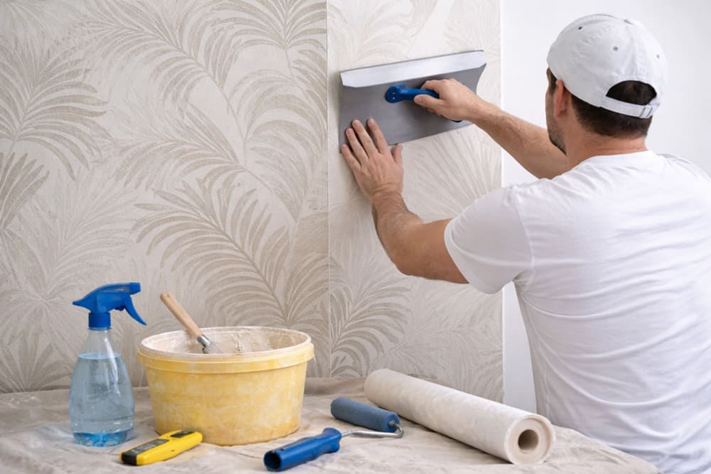 Schrittweises Anbringen einer Tapete mit einem Tapetenglätter an der Wand